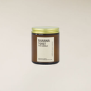 Banana Toast soy candle in a brown glass jar with a gold lid and cream label.