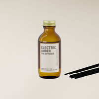 Electric Amber 100ml amber glass reed diffuser with gold cap and black reed sticks.