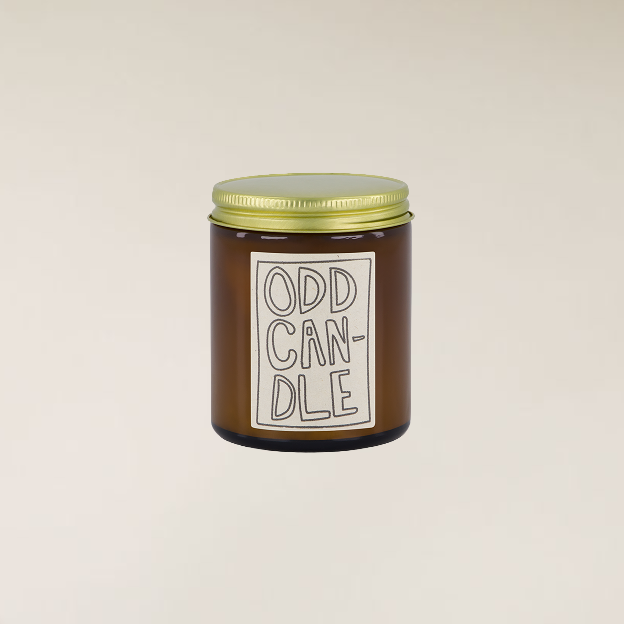 Brown glass Odd Candle with a gold lid and a white label featuring hand-drawn text.
