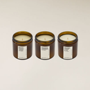 Three large amber glass jar candles with white labels: White Sandalwood, Smoked Lavender, and Brown Sugar & Fig.