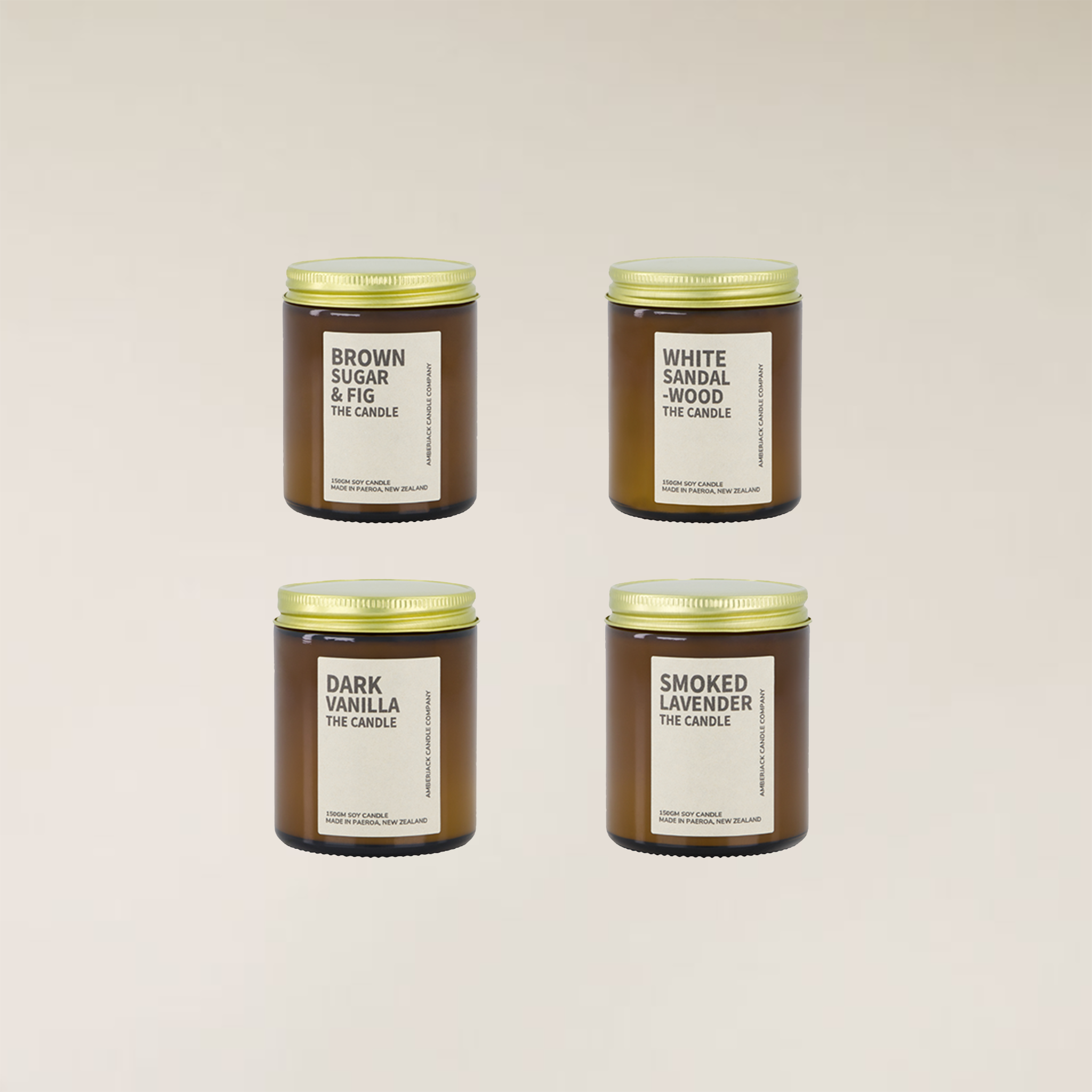 Four amber glass soy candles with gold lids and white labels, featuring different fragrance names.