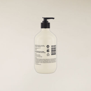 A translucent white pump bottle of hand or body wash with a black dispenser, shown from the back against a solid off-white background.