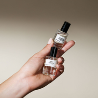 Hand holding two clear 12ml Smoked Lavender and Dark Vanilla perfume oil roll-on bottles with black caps.