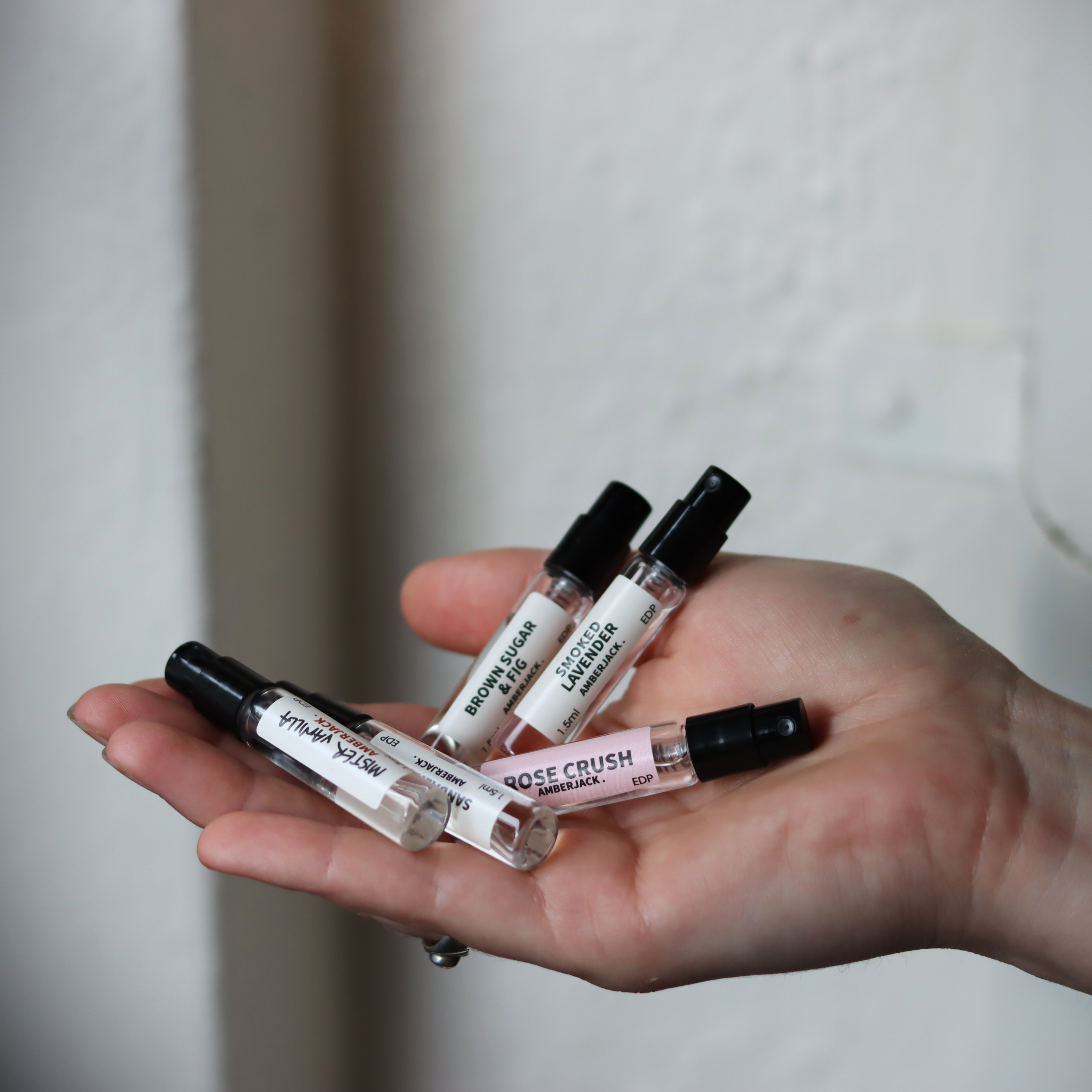5 small perfume sample bottles on a hand