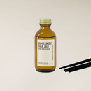 Amber brown glass "Whiskey in a Jar" reed diffuser with gold cap and black reed sticks.
